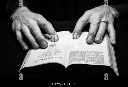 Un homme la lecture de la Sainte Bible à deux mains Banque D'Images