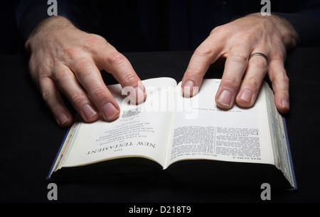 Un homme la lecture de la Sainte Bible avec deux mains. Banque D'Images