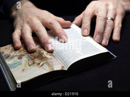 Un homme la lecture de la Sainte Bible avec deux mains. Banque D'Images