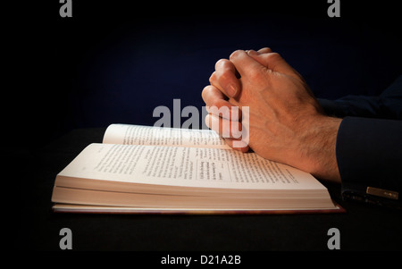 Les mains jointes sur une Bible en priant à Dieu. Banque D'Images