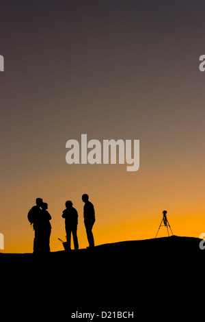 Un photographe avec un trépied, un coucher de soleil dans le désert montres silhouette Banque D'Images