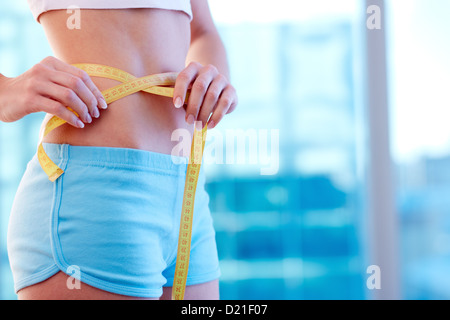 Close-up of a woman in sportswear measuring her waist Banque D'Images