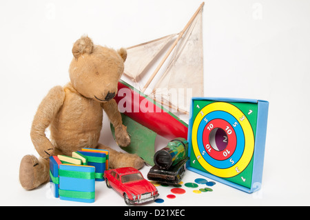 Une collection de bien-aimé simple classique des jouets d'enfants dont un mignon petit ours en peluche, en bois rouge, bateau à voile, et train vert Banque D'Images