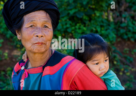 Portrait d'une femme Lisu avec fille sur son dos dans un village, dans le Nord de la Thaïlande hilltribe Banque D'Images