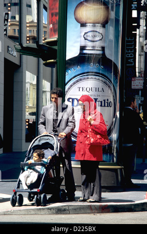 Famille musulmane avec bébé dans la poussette traverse grant street en face de la Tequila publicité Banque D'Images