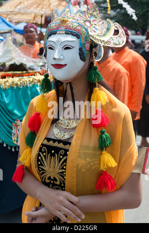 Une femme portant un masque peint traditionnel prend part à une parade de la Fête des moissons dans le village de Tumpang, Java, Indonésie Banque D'Images