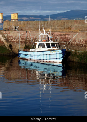 Un petit bateau de pêche se reflète dans les eaux calmes du port de pêche historique de Cromarty, dans les Highlands écossais. Banque D'Images