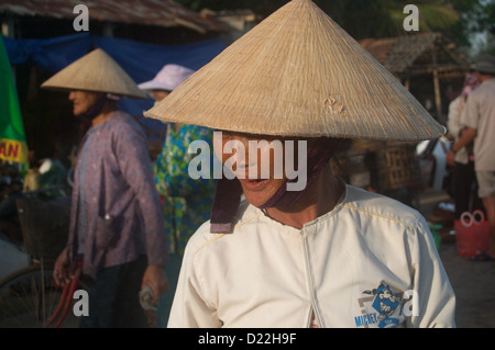 Une vieille dame vietnamienne dans le chapeau conique typique promenades le long du port de la Duy Hai Village de pêcheurs, Hoi An, Vietnam Banque D'Images
