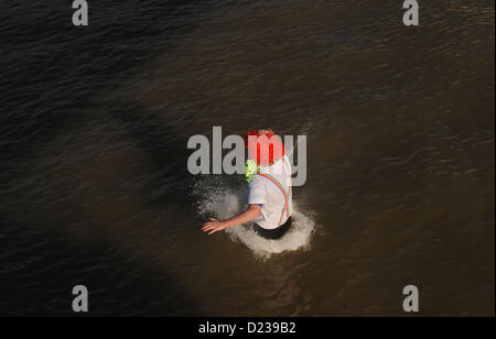 Un clown se précipite pour participer au Leap annuel de Littlehampton où des sauteurs robustes bravent le froid pour plonger dans la rivière Arun le 2013 janvier Banque D'Images