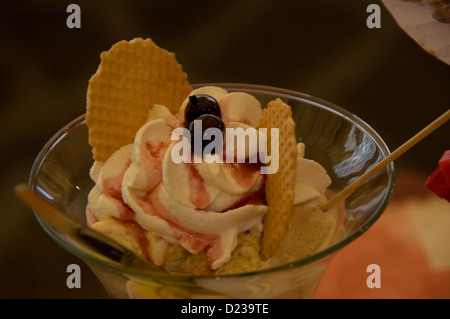 Glace italienne avec biscuit au galette, crème fraîche, cerises noires et un soupçon de sauce aux fraises avec un ventilateur de biscuits, servi dans un restaurant Banque D'Images