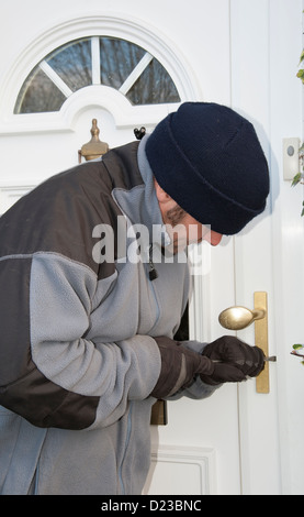 Cambrioleur par effraction dans une maison par la porte avant Banque D'Images