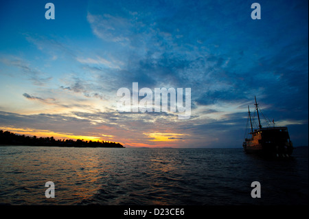 Le yacht en face d'un beau coucher du soleil à Raja Ampat par une île. Journée calme dans la région de Raja Ampat en Papouasie occidentale en Indonésie Banque D'Images