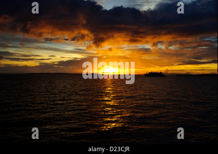 Le coucher de soleil sur l'océan calme plat à Sorong Raja Ampat en Papouasie occidentale. Ci-dessous sombres de l'océan de nuages sombres au-dessus de lumière chaude. Banque D'Images