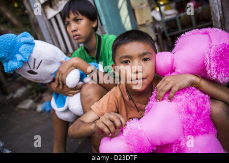 13 janvier 2013 - Bangkok, Thaïlande - Les enfants avec leurs jouets dans le quartier de Bangkok Bang Luang. Le quartier de Khlong Bang Luang lignes (Canal) Bang Luang dans la section de Thonburi Bangkok sur le côté ouest de la rivière Chao Phraya. Il a été établi à la fin du xviiie siècle par le roi Taksin le grand après les Birmans à sac la capitale Siamoise d'Ayutthaya. Le quartier, comme la plupart de Thonburi, est relativement peu développé et criss encore traversé par les canaux qui ont fait de Bangkok célèbre. C'est maintenant une promenade journalière du centre de Bangkok et offre un aperçu de ce que la ville utilisée pour Banque D'Images