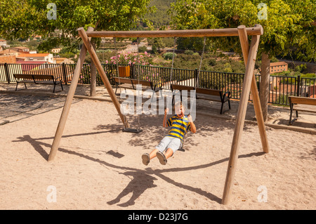 Un garçon jouant sur une balançoire dans le vieux village de Pratdip , Costa Dorada , Espagne Banque D'Images