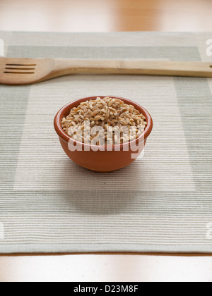 Vue rapprochée de l'orge biologique dans un bol avec une cuillère en bois Banque D'Images