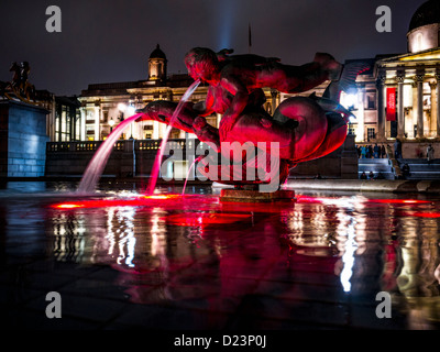 Une photo nocturne des Fontaines d'eau de Trafalgar Square illuminée de rouge avec la galerie nationale de portrait en arrière-plan, le 10 janvier 2013 Banque D'Images