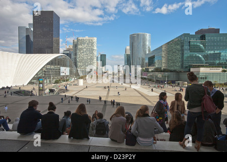 Les jeunes dans les escaliers de la Grande Arche avec vue sur les tours du quartier financier de la Défense à Paris Banque D'Images