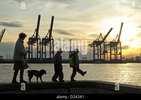 Mère, pour les enfants et le chien marchant le long d'un mur en face du Terminal Burchardkai, port de Hambourg, Allemagne Banque D'Images