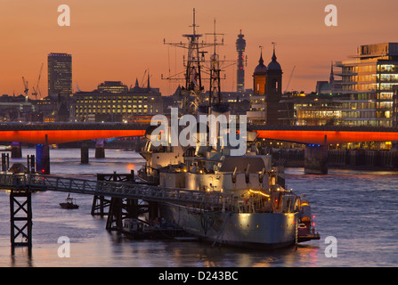 Le HMS Belfast amarré sur la Tamise avec le London Bridge skyline et bureau de poste tour en arrière-plan au coucher du soleil, Londres, Angleterre Banque D'Images