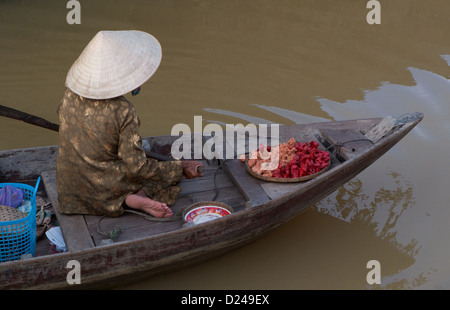 Une dame de lignes du vendeur son petit bateau de pêche le long de la rivière Thu Bon à Hoi An Vietnam Banque D'Images