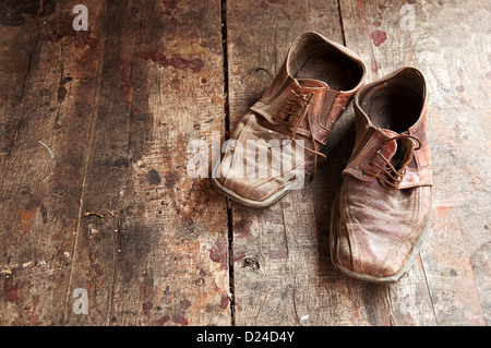 Chaussures en cuir brun sale vieux sur plancher en bois. Banque D'Images