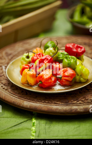 Un plat de piments Scotch Bonnet sur une planche en bois sculpté Banque D'Images