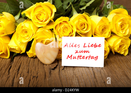 Roses jaunes avec coeur de pierre et une carte avec les mots 'Alles Liebe zum Muttertag' Banque D'Images