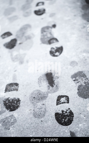 Des pas dans la neige humide sur l'asphalte de la route en milieu urbain Banque D'Images