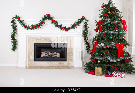 Foyer au gaz naturel avec l'arbre de Noël entièrement décorée dans le séjour d'accueil pendant les vacances Banque D'Images