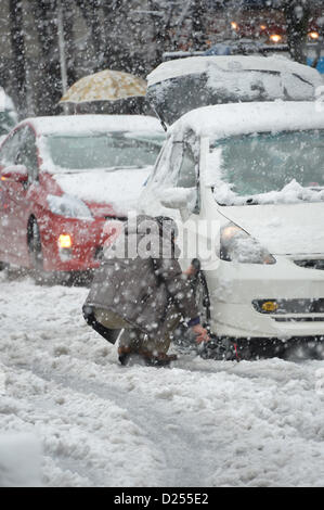 Tokorozawa, au Japon. 14 janvier 2013. Un chauffeur installe des chaînes de pneu dans la neige à Tokorozawa, banlieue ouest de Tokyo, le lundi 14 janvier 2013. Une tempête d'hiver freak pouces de neige, couvrant la zone métropolitaine de Tokyo et ses environs avec des couvertures de première neige de la saison. (Photo de Natsuki Sakai/AFLO) AYF -mis- Banque D'Images