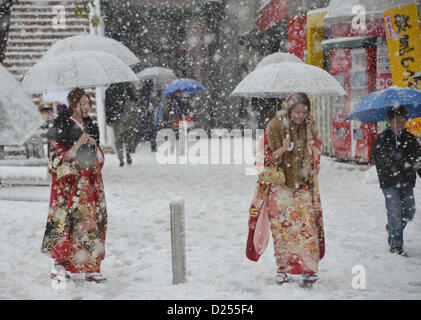 Tokorozawa, au Japon. 14 janvier 2013. Vêtus de robes de cérémonie, manches longues femmes japonaises hâte leur façon d'assister à un passage à l'âge d'une cérémonie à Tokorozawa, banlieue ouest de Tokyo, dans la neige qui tombe le lundi, Janvier 14, 2013. Sur 1 220 000 personnes en 20 ans ont célébré leur passage à l'âge dans tout le Japon. Une tempête d'hiver freak pouces de neige, couvrant la zone métropolitaine de Tokyo et ses environs avec des couvertures de première neige de la saison. (Photo de Natsuki Sakai/AFLO) AYF -mis- Banque D'Images