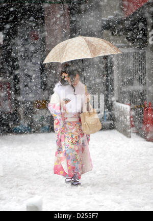 Tokorozawa, au Japon. 14 janvier 2013. Habillée d'une robe à manches longues de cérémonie, une japonaise se précipite sa façon d'assister à un passage à l'âge d'une cérémonie à Tokorozawa, banlieue ouest de Tokyo, dans la neige qui tombe le lundi, Janvier 14, 2013. Sur 1 220 000 personnes en 20 ans ont célébré leur passage à l'âge dans tout le Japon. Une tempête d'hiver freak pouces de neige, couvrant la zone métropolitaine de Tokyo et ses environs avec des couvertures de première neige de la saison. (Photo de Natsuki Sakai/AFLO) AYF -mis- Banque D'Images