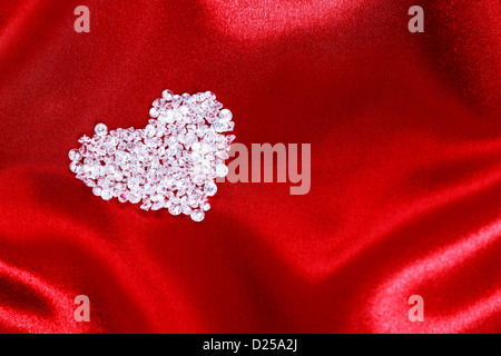 Forme de coeur faits de diamants cz sur un fond de satin rouge. Banque D'Images