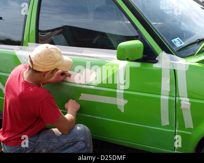 Jeune garçon couleur vert réparation ponçage du mastic de carrosserie Banque D'Images