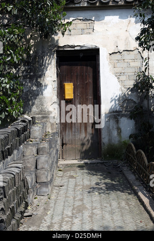 C'est une photo d'une ancienne porte d'entrée dans un vieux village en Chine. C'est dans le bois. Le mur est de couleur blanche. Il semble abandonné. Banque D'Images