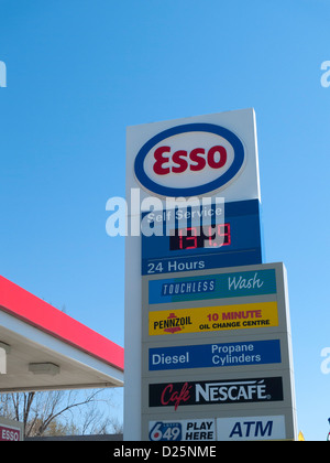 Panneau de station-service Esso à l'extérieur d'une station-service indiquant le gaz prix ouverts 24 heures dans les annonces bleu ciel copie espace En 2012, Canada KATHY DEWITT Banque D'Images