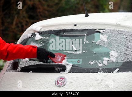 Brighton Sussex UK 14 Janvier 2013 - Jeune femme portant un Cœur rouge veste radio racler la glace et neige sur un Cinquicento Fiat Banque D'Images