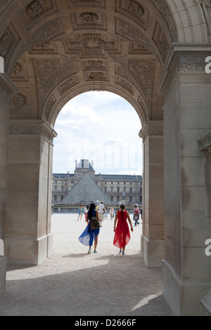 Deux femmes habillées en rouge et bleu voiles à marcher en direction du musée du Louvre à Paris, France Banque D'Images