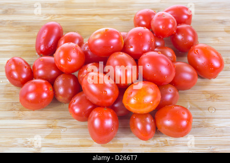 Un groupe de tomates raisins rincés fraîchement sur une planche à découper en bois. Banque D'Images