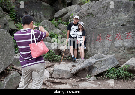 Un couple de contrepartie posent à côté de l'une des nombreuses inscriptions sur la montée vers le haut de Tai Shan, Chine Banque D'Images