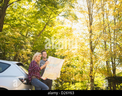 USA, Ohio, Newtown, Couple leaning contre voiture et reading map Banque D'Images