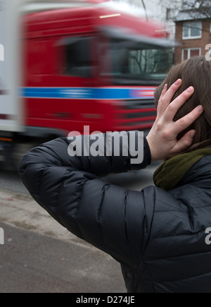 L'illustration montre une femme tient ses oreilles comme un camion conduit par le trafic important dans la région de Hambourg, Allemagne, 11 janvier 2013. Photo : Axel Heimken Banque D'Images