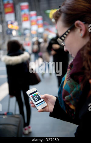 Au sein d'une foule de personnes une jeune femme appelle le réseau Google plus sur son téléphone mobile. Banque D'Images