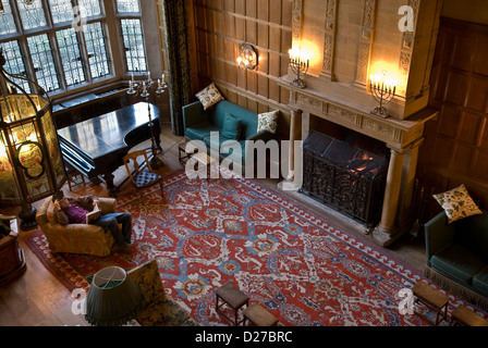 Étudiant la lecture et de détente au coin du feu dans le hall principal du West Dean College, Chichester, West Sussex, UK Banque D'Images
