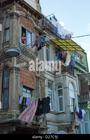Une femme à sa fenêtre donnant sur rue dans quartier pauvre Tarlabasi, Istanbul. Les habitants d'accrocher leurs lave-out de l'autre côté de la rue. Banque D'Images