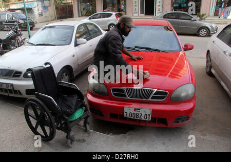 16 janvier 2013 - La ville de Gaza, bande de Gaza, territoire palestinien - Palestinien Ibrahim Abu Thuraya, 28 ans, nettoie une voiture dans la ville de Gaza le 16 janvier 2013. Thuraya a été frappé par un obus israélien. Il a perdu ses deux jambes et un de ses yeux pendant les trois semaines de conflit armé dans la bande de Gaza entre Israël et les militants palestiniens. Le conflit appelé ''L'Opération Plomb Durci'' a donné lieu à environ 1400 morts palestiniens (crédit Image : © Ezz Al-Zanoon ZUMAPRESS.com)/Images/APA Banque D'Images