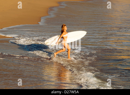 Femme passe dans la mer avec sa planche de surf. Banque D'Images