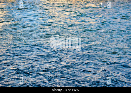 Les vagues de l'eau avec la réflexion du soleil au crépuscule Banque D'Images