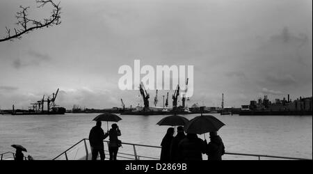 Hambourg, Allemagne, le 1 janvier, 2013 : Visiteurs à Hambourg, HafenCity le long du fleuve Elbe équipée de parasols pour résister à une journée typique météo Hambourg. Banque D'Images